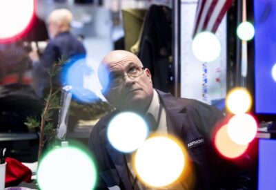 A trader works on the floor as news of the Federal Reserve rate cut decision shows on a TV at the New York Stock Exchange