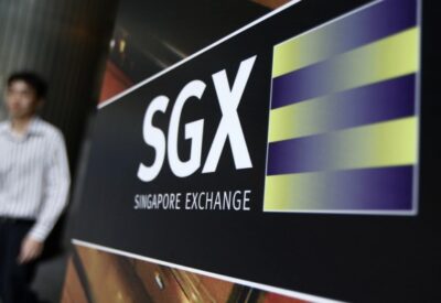 An office worker walks past the logo of SGX