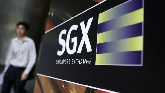 An office worker walks past the logo of SGX