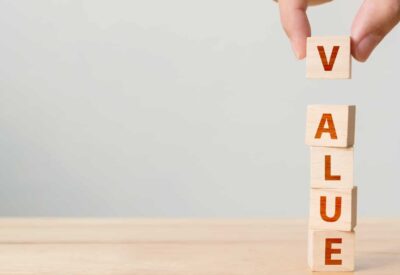 Hand of person putting wood cube block with word VALUE on wooden table